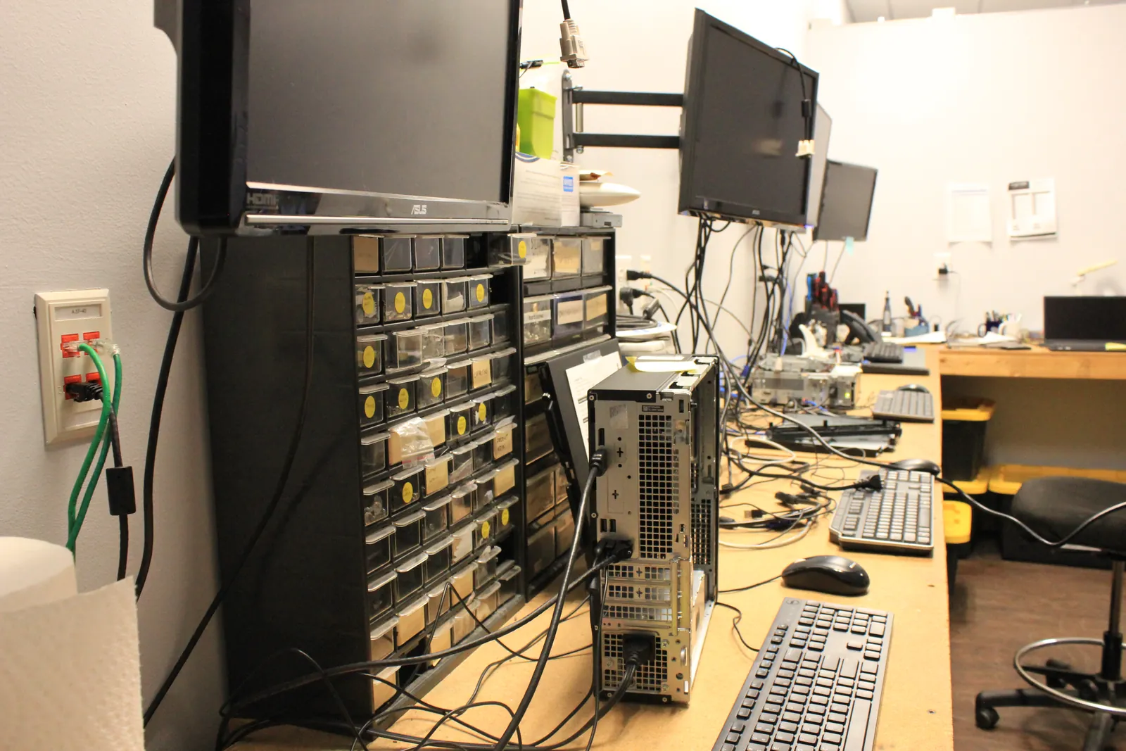 Computer Ties repair workbench with parts bins, monitors and a desktop tower under service